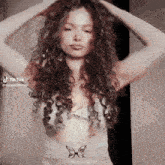 a woman with curly hair is wearing a white top with a butterfly on the waist