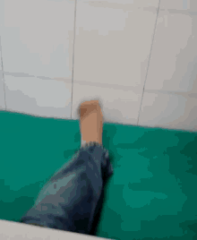 a person 's foot is laying on a green sheet