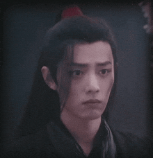 a close up of a man 's face with long hair and a ponytail