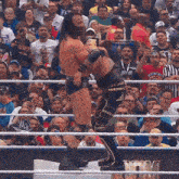 two men are wrestling in front of a crowd with a sign that says ioy