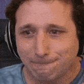 a close up of a man wearing headphones and making a sad face .