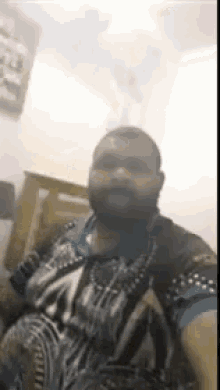 a man with a beard is taking a selfie in a room with a bed in the background .
