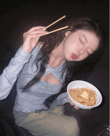 a woman is eating noodles with chopsticks and sticking out her tongue