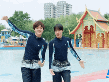 two young men are standing next to each other in front of a building that says neo