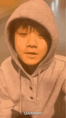 a close up of a person wearing a hoodie with the word dammm on it .