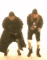a blurry picture of two men standing next to each other .