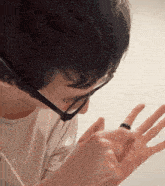 a man wearing glasses looks down at his hand