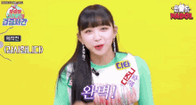 a girl with long black hair and bangs is wearing a green top and earrings .