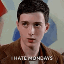 a young man is sitting in front of a painting and says `` i hate mondays '' .