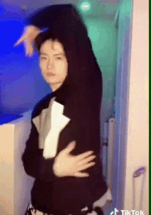 a woman is standing in a room with her arms crossed and a tiktok logo on the bottom right corner