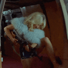a blonde woman is holding a gun in a room