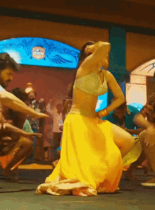 a woman in a crop top and yellow skirt is dancing in front of a harley davidson sign