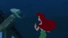 ariel from the little mermaid is sitting on the floor in a room .