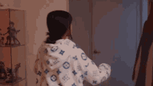 a woman wearing a louis vuitton hoodie is standing in front of a mirror in a room .