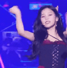 a woman is standing on a stage with her arms in the air and singing into a microphone .