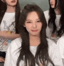 a woman with long hair is sitting in front of a group of women wearing white shirts .