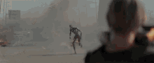 a woman stands in front of a large explosion