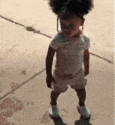 a little girl standing on a sidewalk wearing white shoes