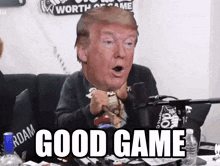 a man sitting in front of a microphone with donald trump 's face on his head and the words good game below him
