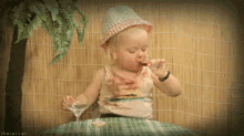 a little girl wearing a hat is drinking from a glass