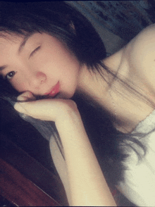 a girl with long black hair is taking a selfie with her hand on her face