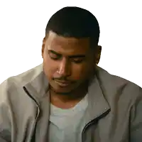 a man wearing a jacket and a grey shirt looks down with his eyes closed