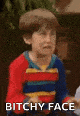 a young boy in a superhero costume is making a funny face and saying `` bitchy face '' .
