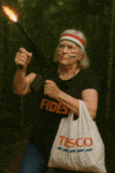 an older woman holding a gun and a tesco bag