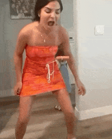 a woman in a red dress is standing on a wooden floor holding a rope .