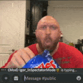 a bald man in a red shirt is eating a bag of lays chips