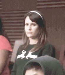 a woman wearing a headband and a green sweater with white deer on it