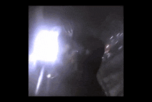 a person is standing in a dark room with a light shining through the window .