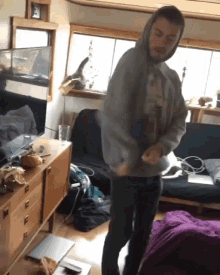 a man in a hoodie is dancing in a messy living room