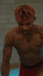 a shirtless man in red boxer shorts is standing in a pool .