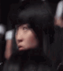 a woman with her eyes closed is sitting in a crowd of people .