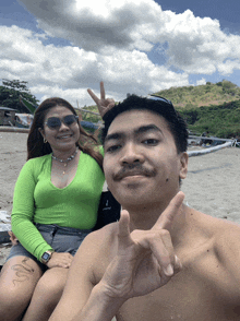 a man giving a peace sign next to a woman in a green top