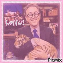 a man in a suit and tie is holding a tiger cub in his arms and says hello !