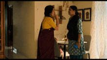 two women standing next to each other with one holding a cell phone