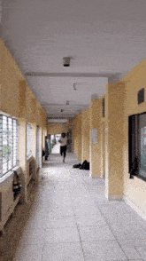 a long hallway with yellow walls and a few windows