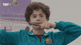 a young boy is holding a bow and arrow in front of a trt1 sign