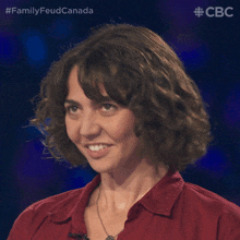 a woman with curly hair is smiling in front of a blue background with the words familyfeud canada on it