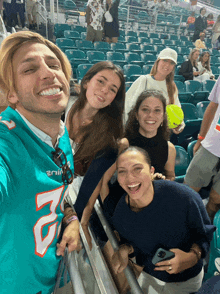 a man wearing a miami dolphins jersey is taking a selfie with his friends