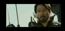 a man with a beard is holding a sword in a movie .