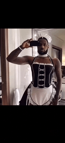 a man in a maid costume is taking a picture of himself in the mirror