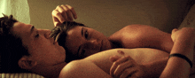 a man and a woman are laying on a bed with the woman touching the man 's hair