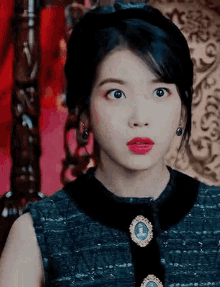 a close up of a woman wearing a black dress and red lipstick .