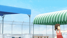 a girl is standing under a green and white striped awning