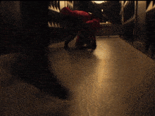 a person in a red suit is crawling on the floor in a dark hallway