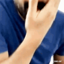a man in a blue shirt is talking on a cell phone ..