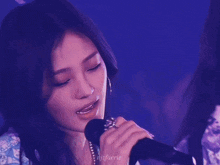 a close up of a woman singing into a microphone with the name njffaerie on the bottom right
